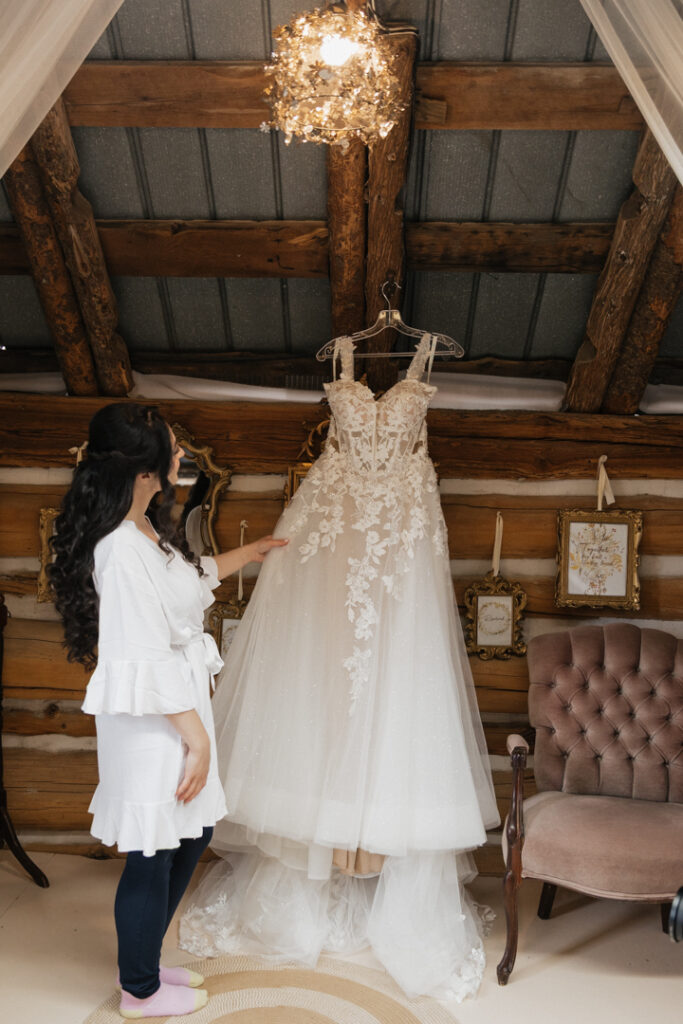 Bride with wedding dress from La Maison Boutique hanging in the barn at The Herb Garden in Almonte, ON